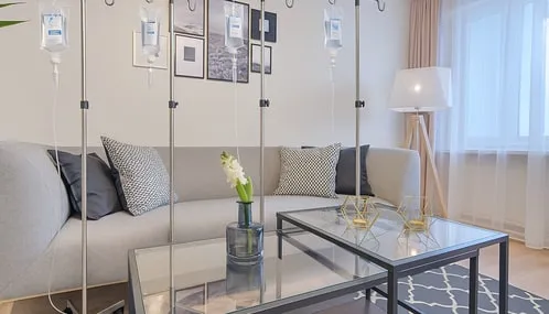 IV drip stands beside a sofa in a bright living room