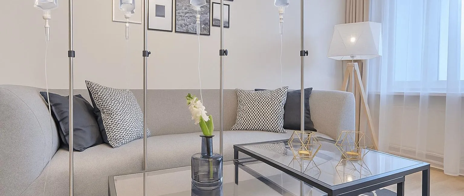 IV drip stands set up beside a sofa in a bright living room