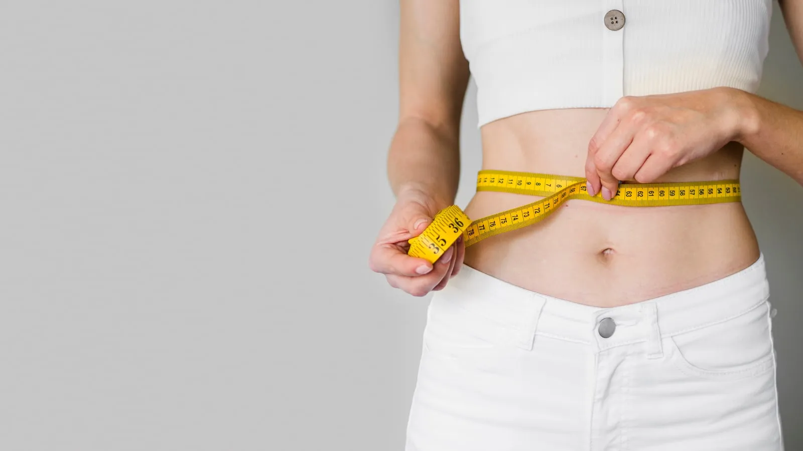 A person measuring their waist with a tape measure